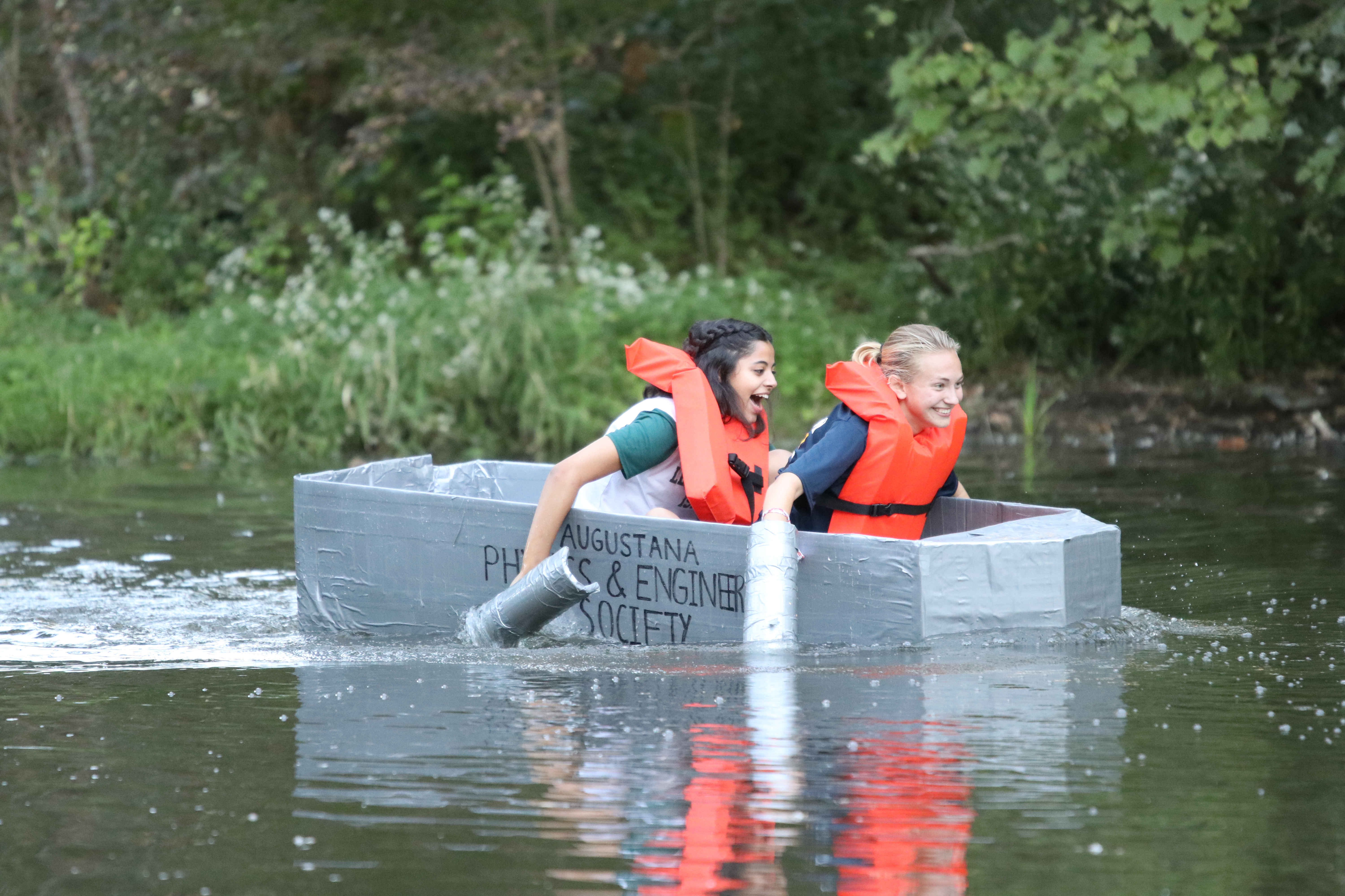 Two students in a handcrafted cardboard boat participate in a homecoming week regatta. 