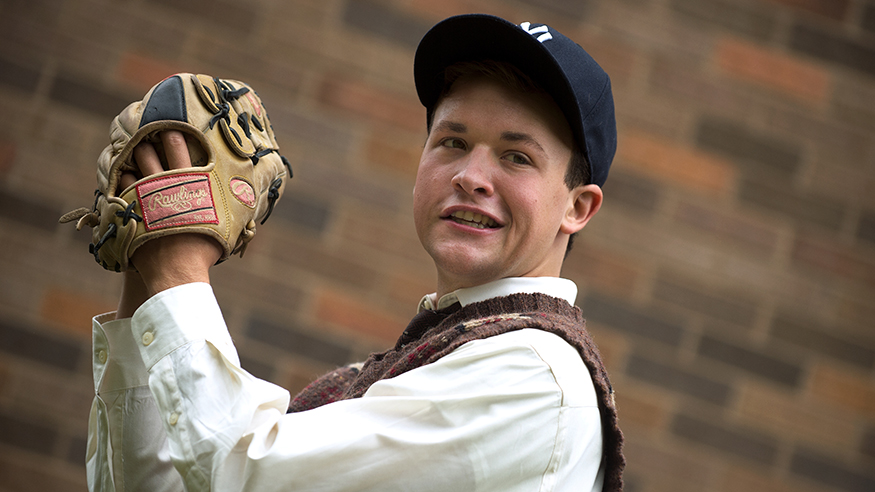A student with a baseball, mitt and cap in a theatre performance