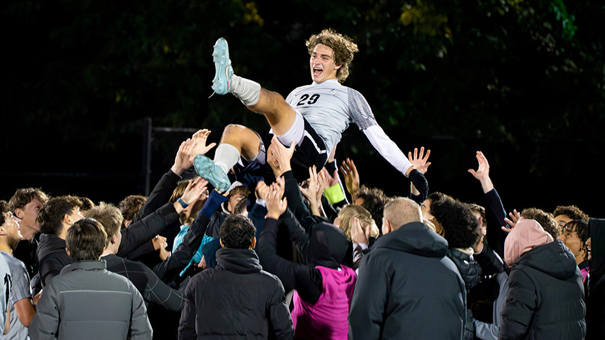 A soccer player is hoisted into the air by a crowd of people after a game