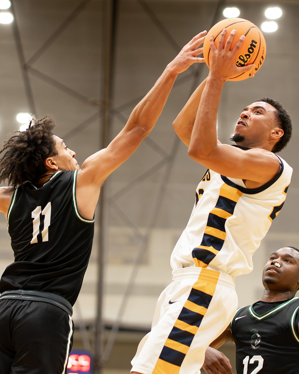 An Augustana basketball player prepares to make a shot while a competing student-athlete tries to block