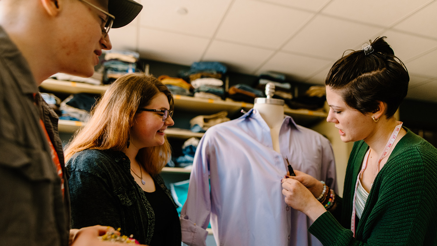 Three students in the theatre costume shop prepare a button-down shirt for a performance