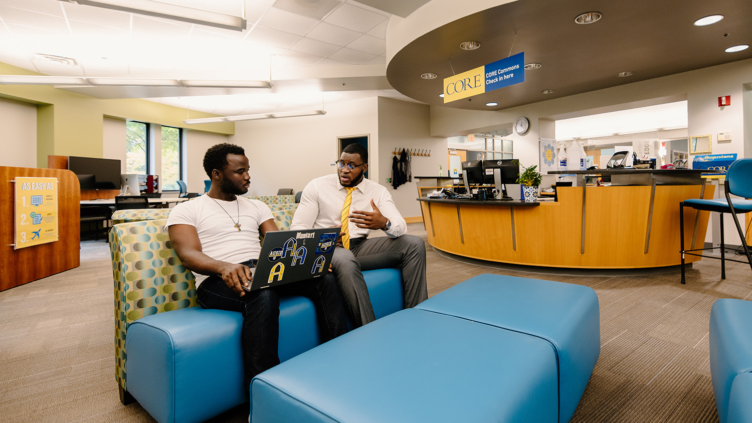 A student with a laptop adorned in Augustana stickers talks with a CORE career coach