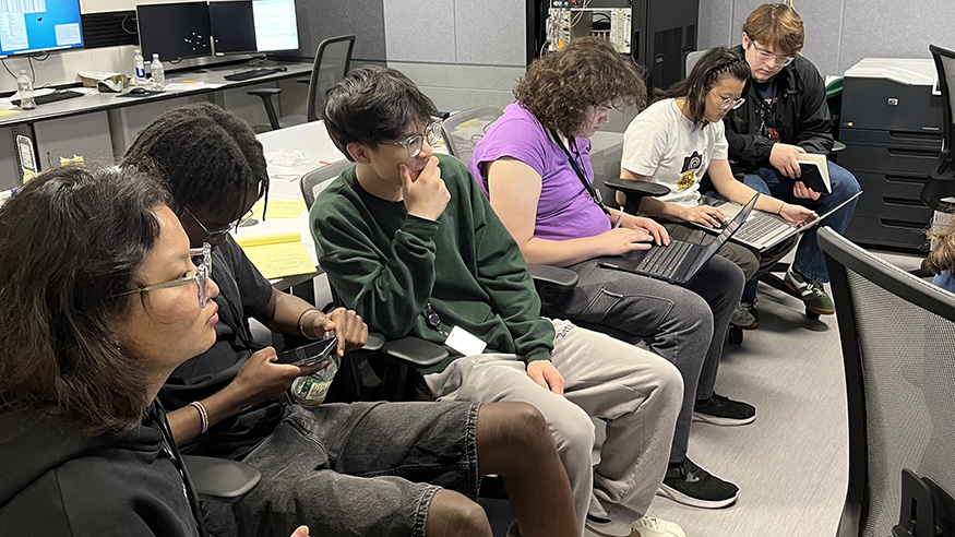 Students sitting in chairs with laptops