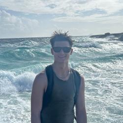 A man posing for a photo with the ocean and waves in the background