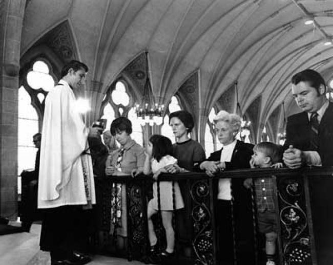 Campus Church Pastor Richard Swanson dispenses communion at the College Chapel in 1970.