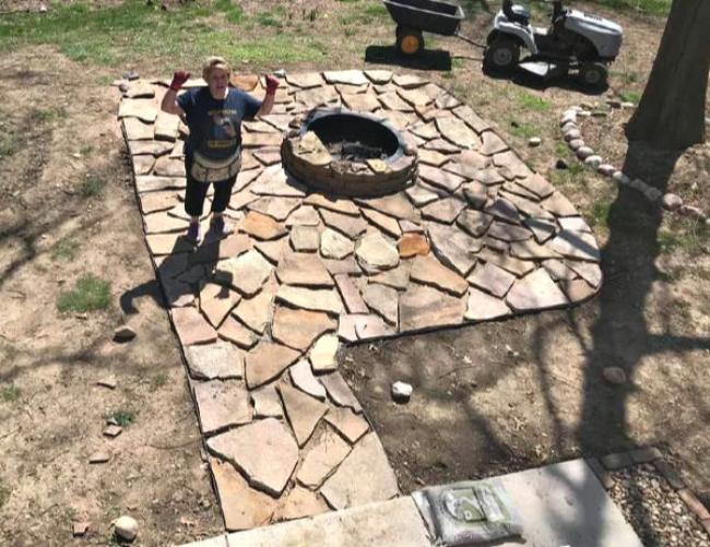 Laura standing around brown bricks with a firepit in the middle in the ground