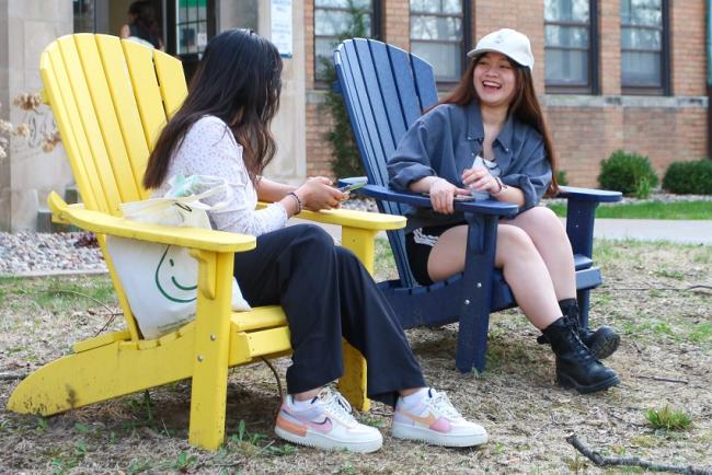 Students talking in Adirondack chairs