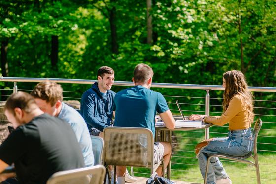 three students talking at a table outdoors