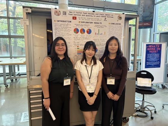 Three students standing in front of a poster