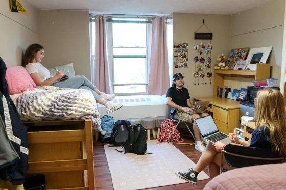 Three students sitting in a dorm room. 