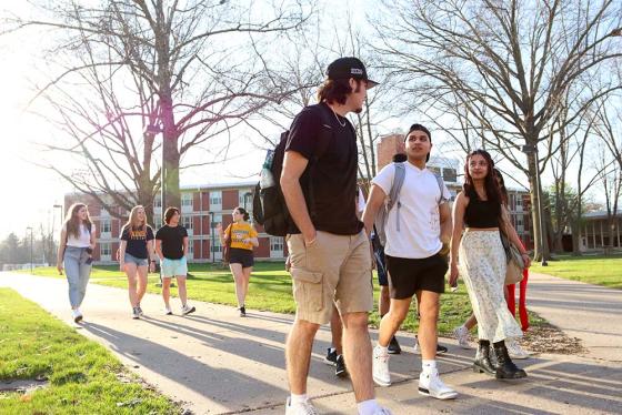 A group of students walking outside on a sidewalk on campus. 