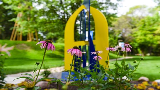 Photo of flowers blooming in front of a blue and gold A statue
